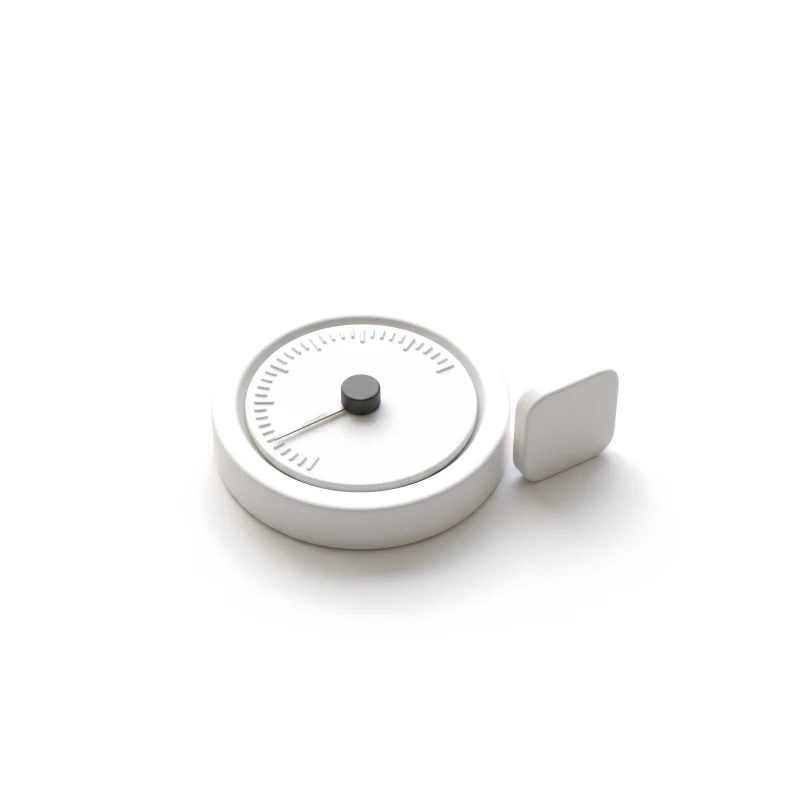 A round white ceramic dial with a steel needle a short way along its ticks and a graphite centre knob, a ceramic app-icon tile standing beside it.