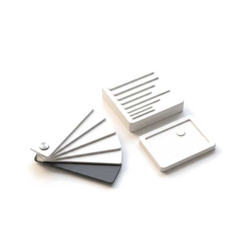 A fan of white ceramic colour swatches with one graphite card, beside a ribbed type block and a picture tile.