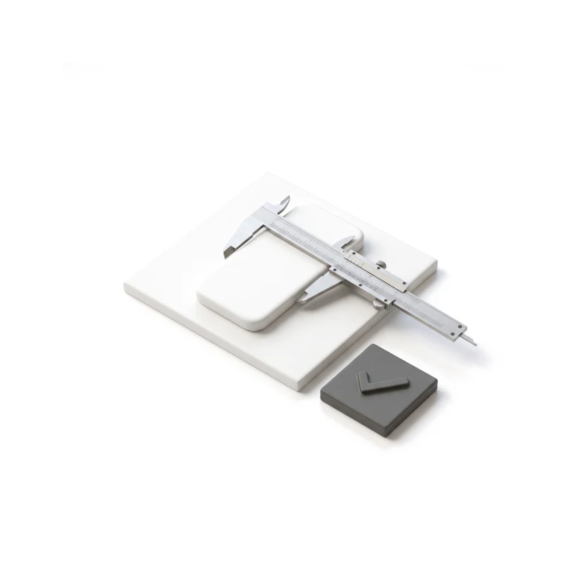 A steel caliper closed around a white ceramic phone blank on a ceramic tile, a graphite check tile beside it.