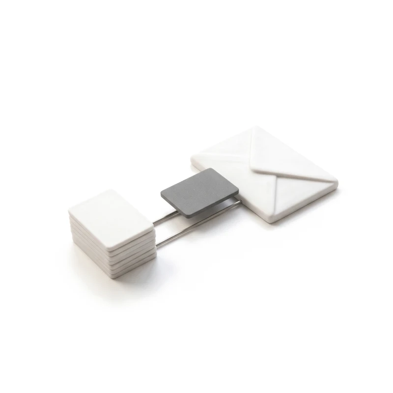 A stack of ceramic cards and a ceramic envelope joined by thin steel rails, a graphite card travelling along them.