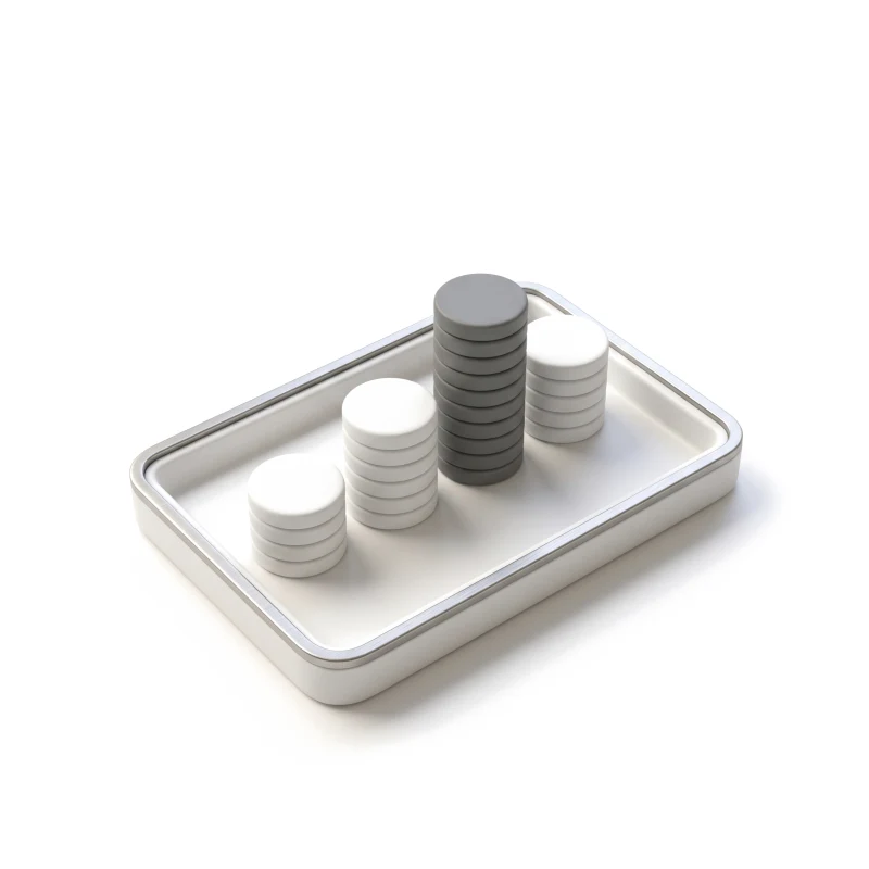 A steel-rimmed white ceramic tray holding stacks of blank ceramic discs of different heights, the tallest in graphite.