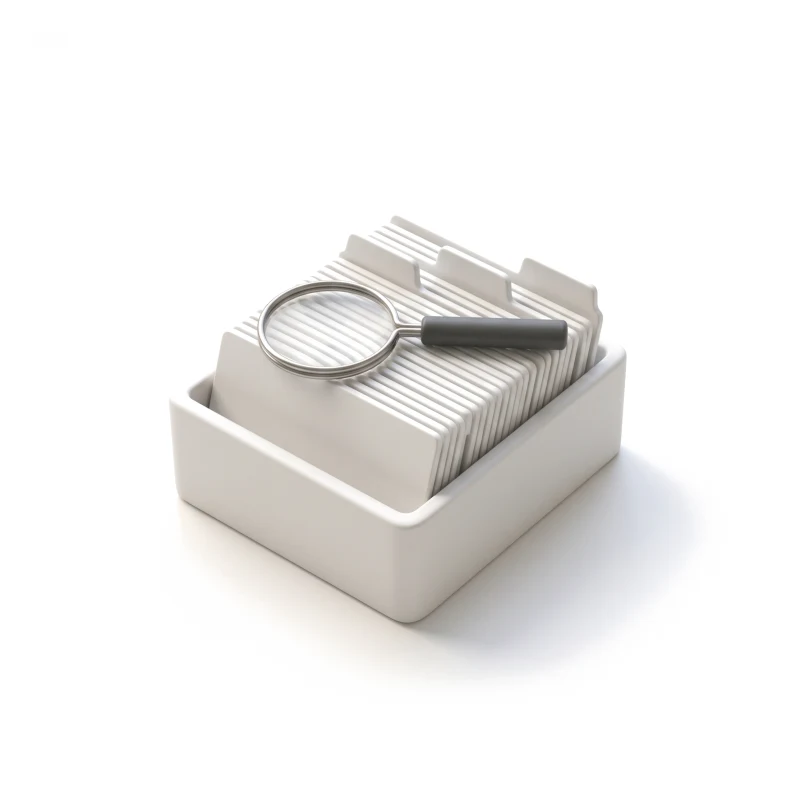 A white ceramic card index with tabbed dividers, a thin steel magnifying glass with a graphite handle resting on it.