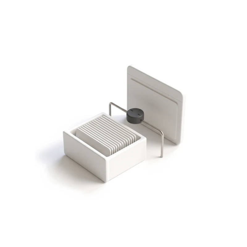 A ceramic drawer of identical cards joined by a steel rod to an upright ceramic panel, a round graphite dial on the rod between them.