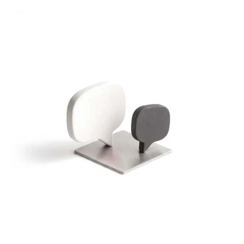 Two ceramic speech bubbles facing each other on a steel base, the smaller one in graphite.
