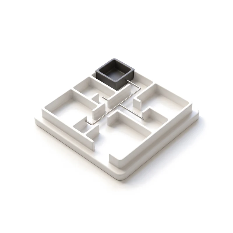 A white ceramic floor-plan model of rooms joined by corridors, one room in graphite.
