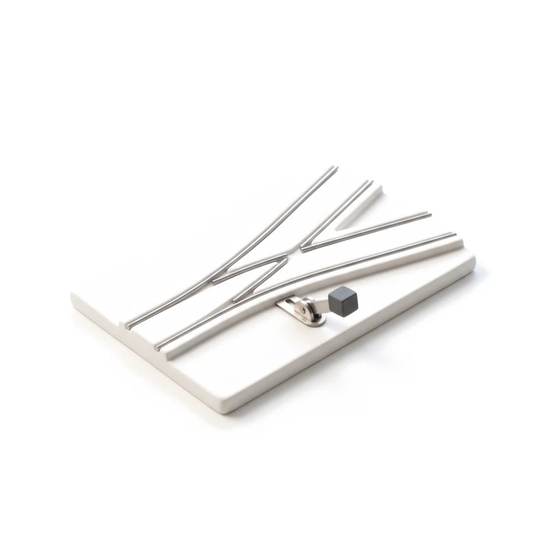 A ceramic plate where one steel-railed track splits in two, a small steel lever with a graphite knob at the split.