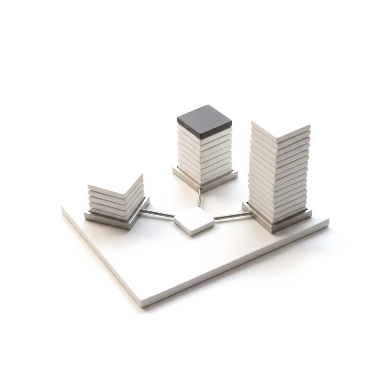 A ceramic base plate with three stacks of tiles joined by thin steel rods to one small tile, one stack capped in graphite.