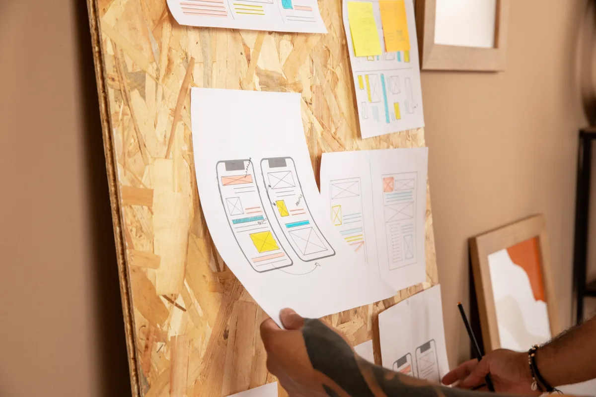 A man displays a paper on a bulletin board, illustrating strategies for optimizing user flow in UX design.