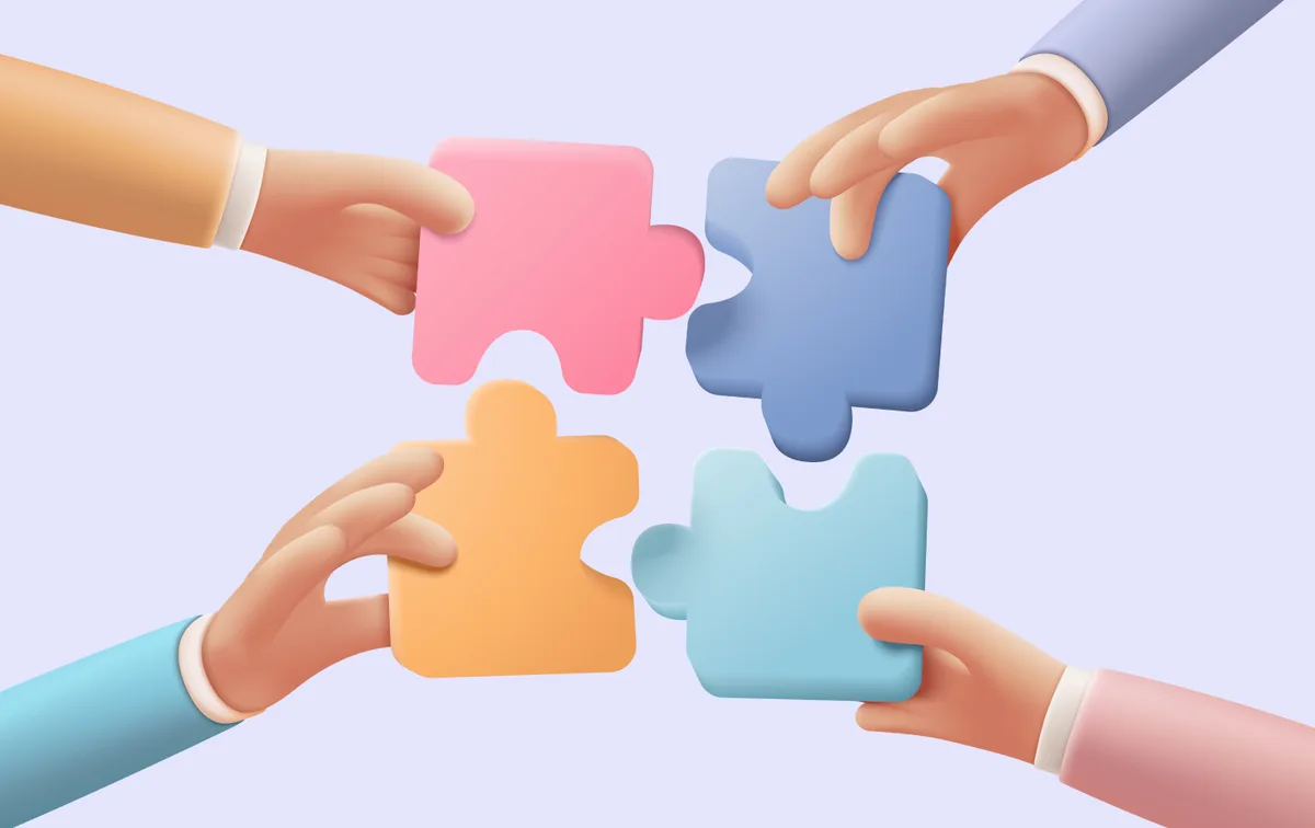 Four hands collaboratively assembling puzzle pieces, symbolizing teamwork in enterprise application design for efficient development.
